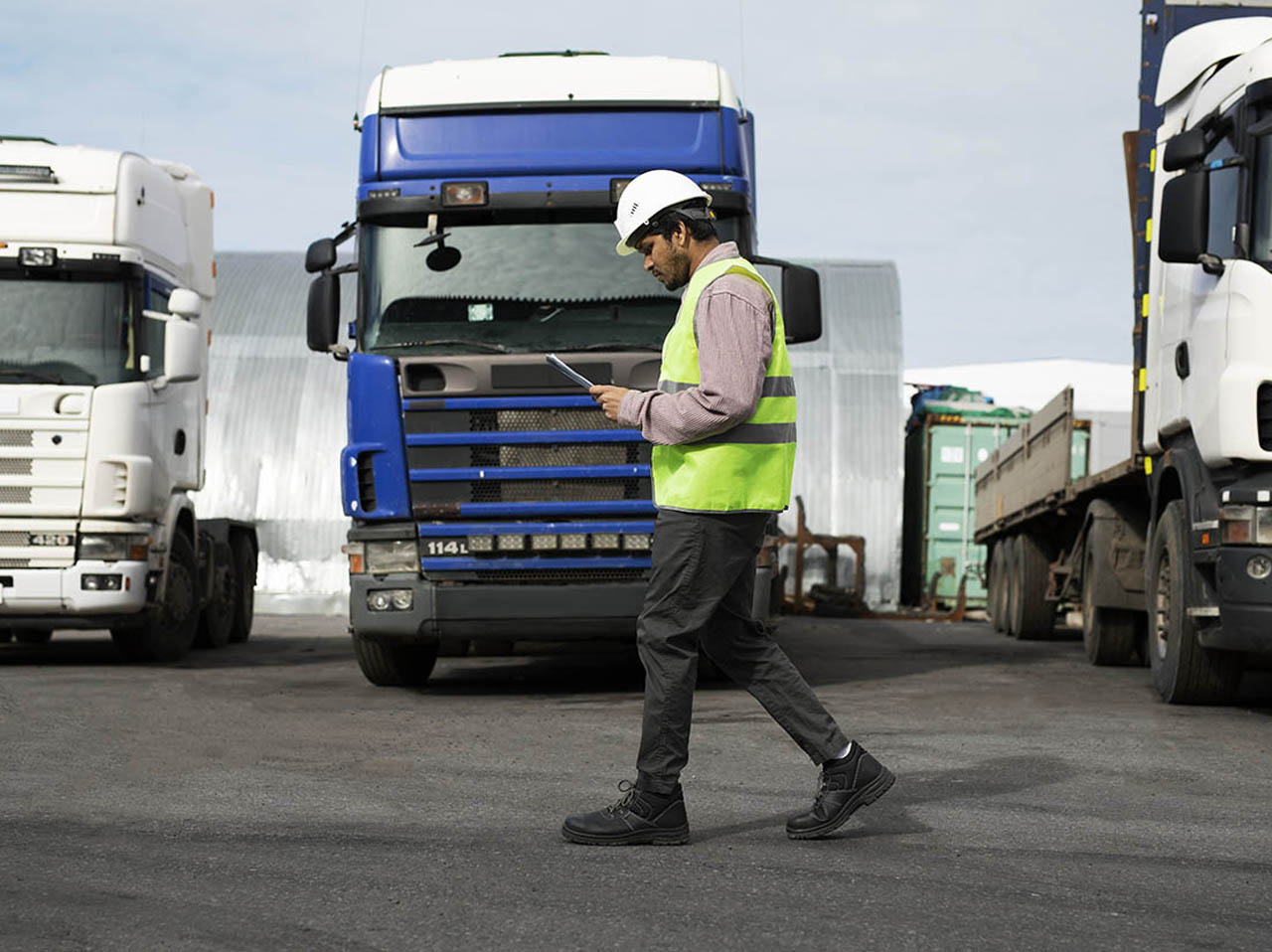 Profissional inspecionando carga com caminhões de transporte